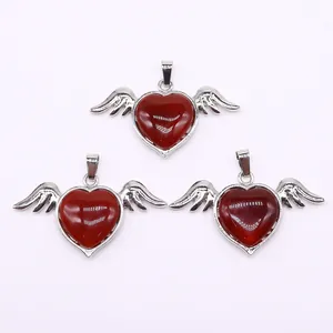 Macro detail of three red agate heart pendants with silver angel wings and bail