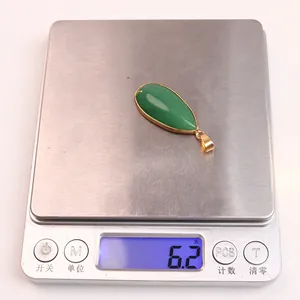 Détail macro d'un pendentif goutte d'aventurine verte de 6,2 g sur une balance