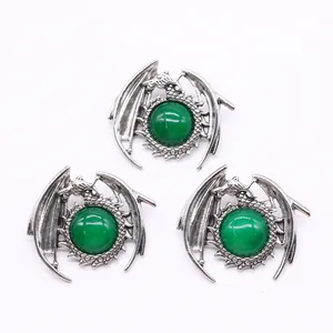 Macro shot of three vintage silver dragon charms with emerald green stone accents