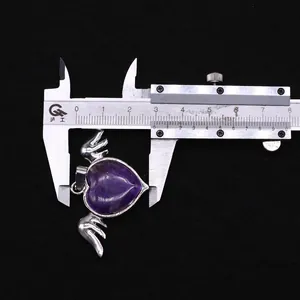 Macro shot showing heart-shaped amethyst pendant width with metal wings on caliper
