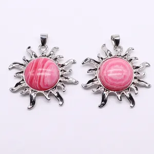 Detail von silbernen Sonnenanhängern mit runden Inlays aus rosa Naturstein-Elementen