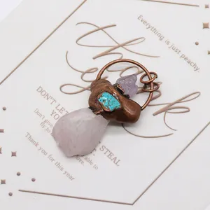 Détail d'un pendentif fait main en améthyste et quartz rose avec fil de cuivre enroulé