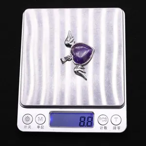 Detail shot of heart-shaped amethyst pendant with silver wings on a digital scale weighing 8.8g