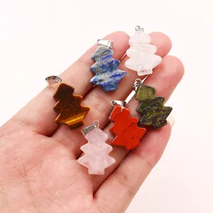 Natural gemstone Christmas tree pendants in rose quartz and lapis lazuli held in hand