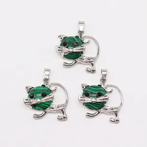 Detalle de colgantes en forma de gato con piedras de malaquita verde y acabado plateado