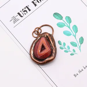 Detailed view of irregular natural agate stone pendant with red-brown banding and copper rim