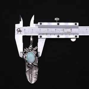 Makroansicht eines Vintage Federanhängers mit blauem Stein und Maßband zur Größenprüfung