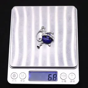 Colgante de gato con piedra natural azul pesado en báscula digital mostrando 6.8g peso