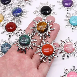 Sonnenanhänger mit Naturstein-Inlay und versilberter Oberfläche in der Hand gehalten