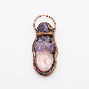 Close-up of handmade bronze pendant with raw purple crystals and pink agate slice detail