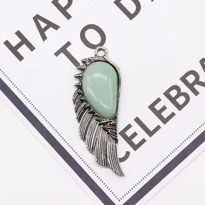 Detail of silver angel wing pendant with teardrop green gemstone on display card