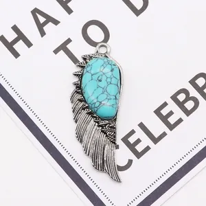 Macro detail of angel wing pendant with turquoise stone inlay and engraved feathers