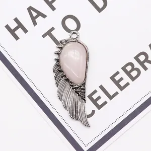 Detail of wing-shaped pendant with pink teardrop stone and silver metallic feathers