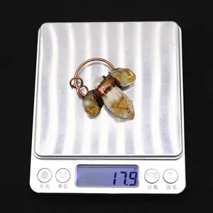 Macro shot of a raw citrine crystal pendant wrapped in bronze wire on a digital scale