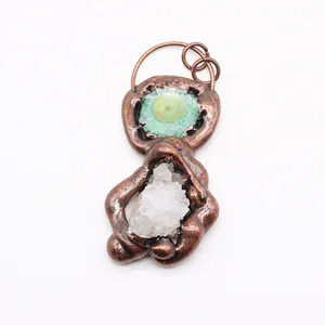 Detailed view of handmade bronze pendant featuring green gemstone and white quartz crystal