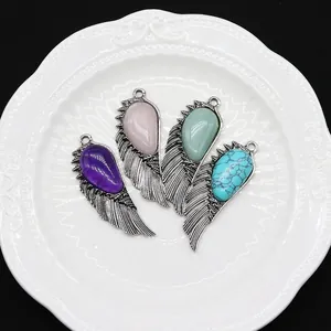 Set of four natural stone wing pendants in assorted colors on a white vintage plate