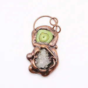 Detail of handmade bronze pendant featuring green agate slice and clear quartz crystals