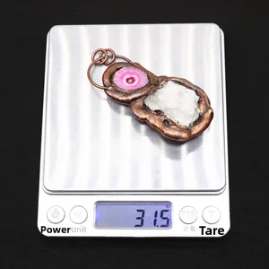 Detail of pink crystal and white quartz druzy pendant on a scale weighing 31.5 grams