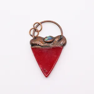 Detalle de colgante triangular rojo con acabado en bronce texturizado e incrustación opal