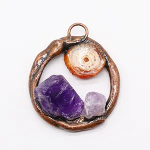 Macro-opname van ronde bronzen hanger met ruwe amethist en oranje minerale stenen