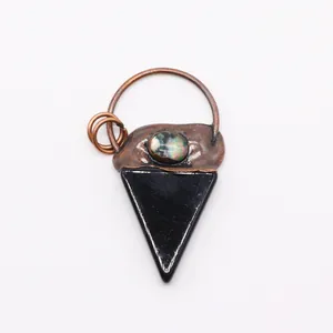 Detalle de colgante vintage de cobre con piedra triangular negra y nácar natural