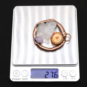 Close-up van handgemaakte natuurstenen hanger met 27,6g gewicht op digitale weegschaal