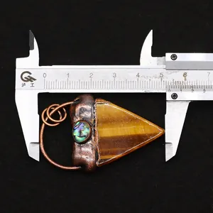 Detalle de colgante triangular de ojo de tigre con regla que mide unos 5,8cm de largo