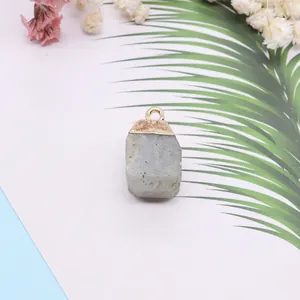 Pendentif carré en pierre naturelle grise avec fermoir en métal doré sur fond épuré