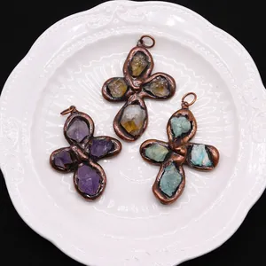 Three natural crystal cross pendants in antique copper frames on a white ceramic plate