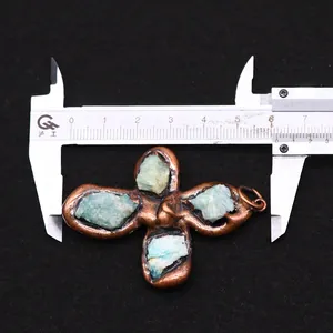 Measurement of copper four-leaf flower pendant with natural green stones on a caliper
