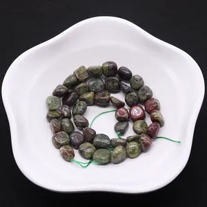 Cuentas de jaspe sangre de dragón naturales pulidas en cordón verde en plato blanco