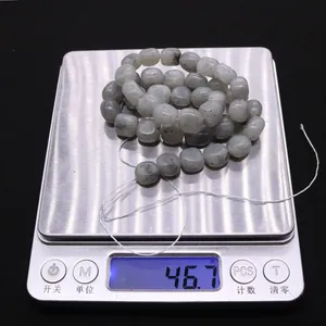 Flat irregular natural labradorite stone beads shown on a scale weighing 46.7 grams