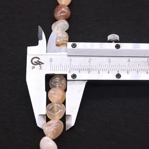 Macro view of measuring 8mm natural cherry blossom agate beads with a metal caliper