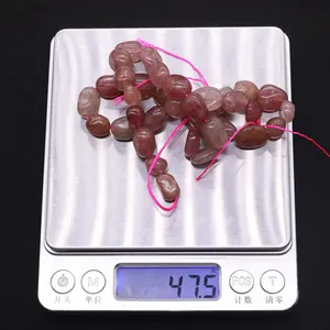 Gros plan de perles irrégulières en quartz fraise naturel sur une balance de précision
