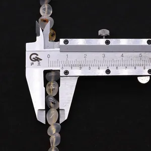 Macro shot measuring 8.5mm irregular natural agate stone beads using a metal caliper