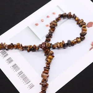 Polished natural irregular tiger eye stone beads on a magazine for DIY jewelry making