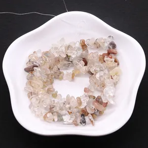 Irregular natural rutilated quartz stone beads for DIY jewelry making on white ceramic tray