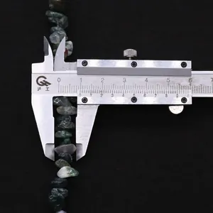 Detail showing irregular Indian moss agate stone beads measured by a caliper on black fabric