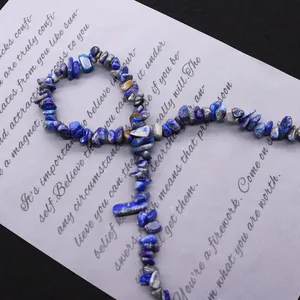 Natürliche Lapislazuli Splitterperlen in Ankh-Kreuzform auf strukturiertem Hintergrund