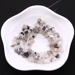 Irregular black rutilated quartz crystal chips on a white plate for DIY jewelry making