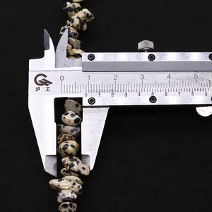 Medición de una cuenta de piedra de jaspe dálmata natural con un calibre digital