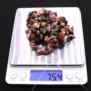 Macro detail of 75.4g irregular polished rhodonite stone beads on a digital scale