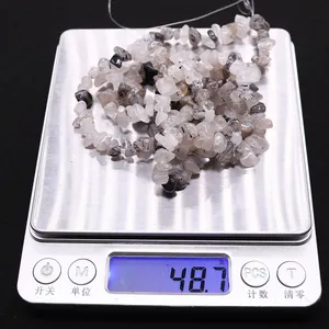 Macro detail of irregular black rutilated quartz crystal beads on a digital scale