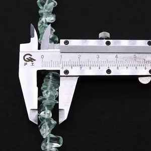 Macro detail of irregular green natural stone beads measured by a caliper showing 10mm size