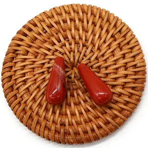 Close-up of polished teardrop red jasper stones with natural textures on a woven base