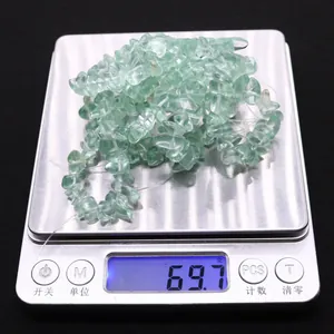 Irregular green fluorite crystal chips on an electronic scale weighing 69.7 grams