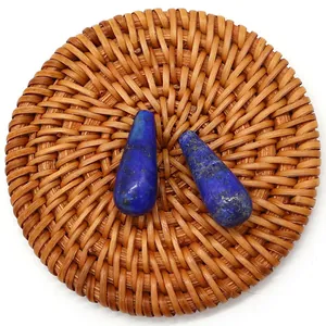 Pair of teardrop-shaped lapis lazuli beads with natural gold flecks on a woven mat