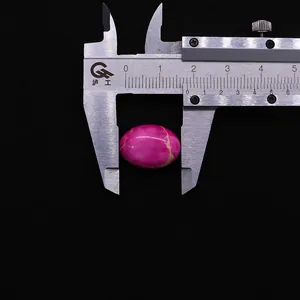 Gros plan d'un cabochon ovale en pierre impériale rose mesuré sur du velours noir
