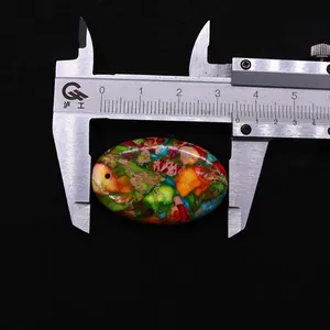 Macro shot of oval colorful natural stone pendant being measured by calipers