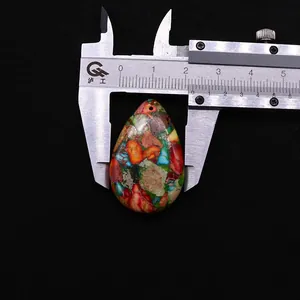 Macro shot of colorful teardrop stone pendant with ruler showing 2.6cm width